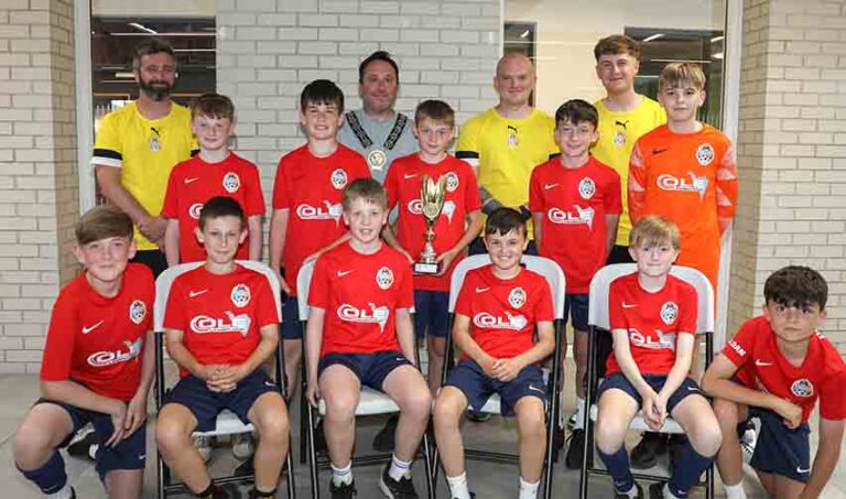 NMDDC Chairperson, Councillor Pete Byrne with the six youth teams across the 2013–2017 age groups who represented the district at the prestigious 2025 Nations Cup held in Barcelona, and their coaches, Ben Ryan, Conor Fegan, Dylan Morgan-Longfield and Ethan Doyle (not present).